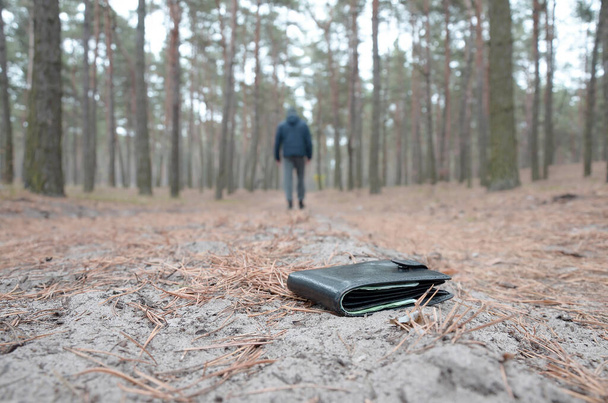 少年はロシアの秋のモミの木の道でユーロ紙幣で財布を失う。不注意で財布の概念を失う - 写真・画像