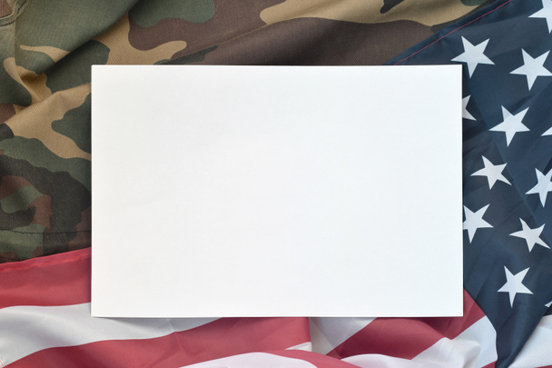 Czysty papier leży na fladze Stanów Zjednoczonych Ameryki i złożonej wojskowej kurtce mundurowej. Symbole wojskowe konceptualny baner tła i miejsca na tekst - Zdjęcie, obraz