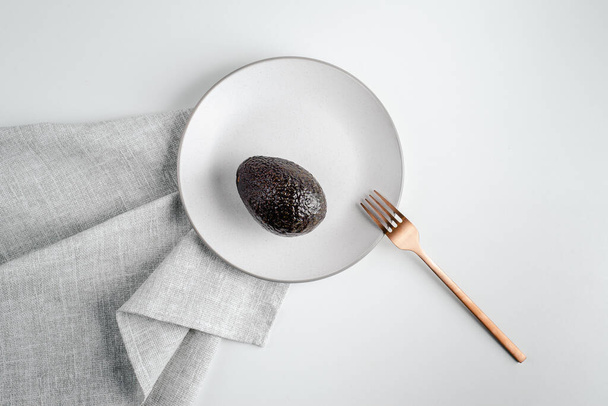 L'avocado è sul piatto. Stile di vita sano, cibo super. Cucchiaio e forchetta d'oro. Posto per testo - Foto, immagini