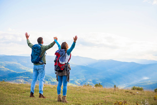 Happy travelers couple conquered top of mountain, raises hands up - Foto, Imagen