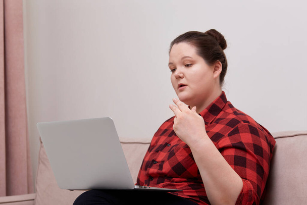 Beautiful woman plus size model working online with laptop on her lap. - Zdjęcie, obraz