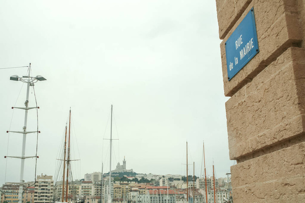 Die Kirche Notre Dame de la Garde, auch Bonne Mere genannt, von der Rue de la Mairie (was auf Französisch Rathausstraße bedeutet) aus gesehen mit den Booten des Vieux-Hafens in Marseille, Südfrankreich - Foto, Bild