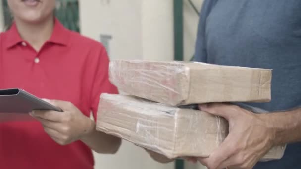 Nainen toimitus työntekijä punainen tuo paketteja - Materiaali, video