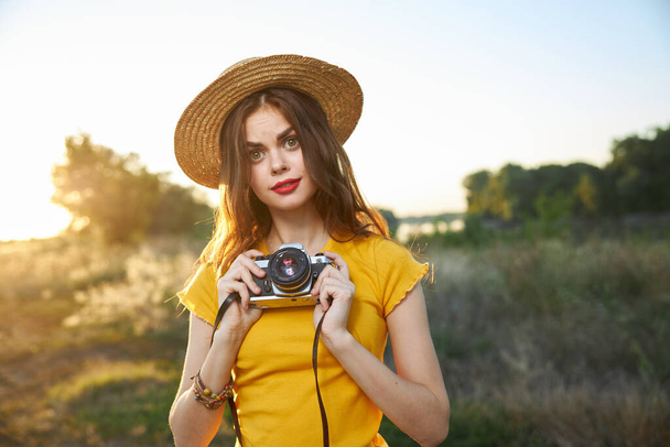 Pretty woman with camera on nature fresh air hat red lips hobby - Foto, Imagen