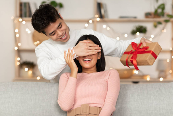 Муж дарит рождественский подарок жене, делая сюрприз дома - Фото, изображение