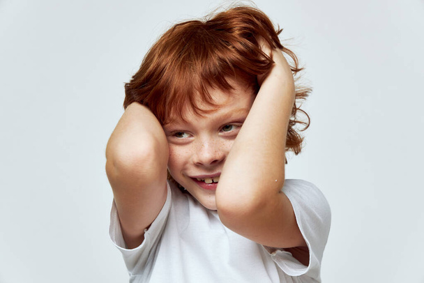 Vidám vörös hajú fiú tartja a fejét mosoly vágott kilátás közelről  - Fotó, kép
