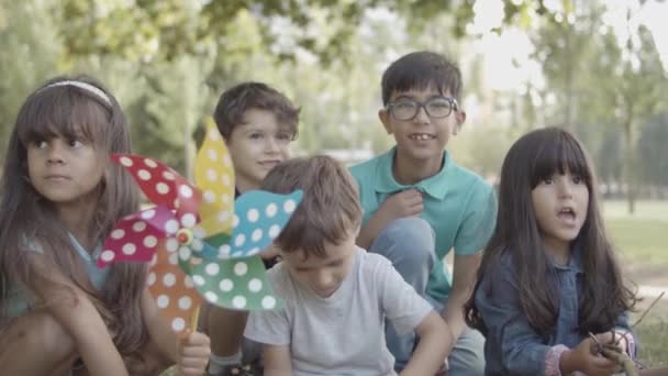 Gruppo di bambini multietnici seduti insieme sulla lezione all'aperto - Filmati, video