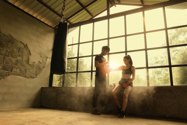 Entraîneur masculin avec boxeur féminin et lumière orange en arrière-plan. - Photo, image