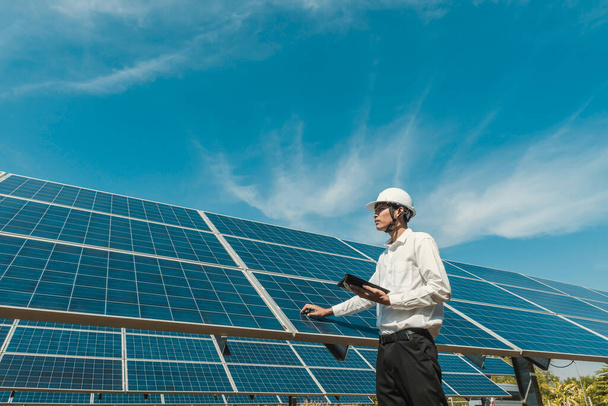 Niedrigwinkel-Ansicht des Solarparks (Sonnenkollektor) mit Technikern, die den Betrieb des Systems überprüfen, Alternative Energie zur Energieeinsparung der Welt, Photovoltaik-Modulidee zur Produktion sauberer Energie. - Foto, Bild