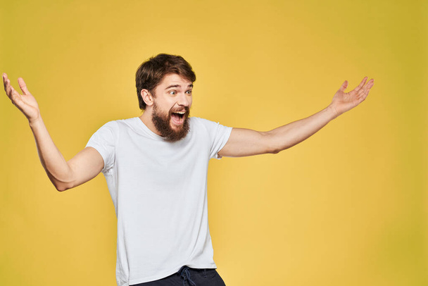 Чоловік жестикулює руками емоції спосіб життя біла футболка жовтий ізольований фон
 - Фото, зображення