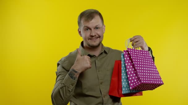 Χαρούμενος άνθρωπος δείχνει Black Friday επιγραφή από τσάντες ψώνια, χαμογελώντας ικανοποιημένοι με χαμηλές τιμές - Πλάνα, βίντεο