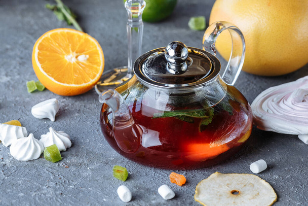Fruit tea with mint, oranges and cranberries on a decorative background. Hot winter drinks. A teapot of hot tea. - Foto, imagen