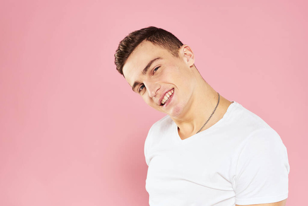 Веселый красивый мужчина в белой футболке эмоции розовый изолированный фон - Фото, изображение