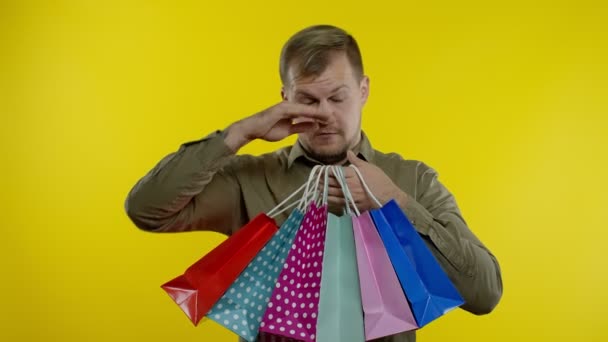Mann hebt Einkaufstüten, sieht zufrieden aus, genießt Rabatte am Black Friday - Filmmaterial, Video