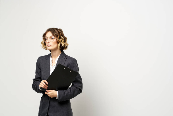 femme d'affaires dans un costume avec des documents dans les mains fond clair coiffure bouclée - Photo, image