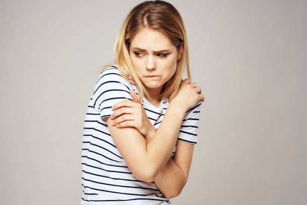 Жінка в смугастій футболці тримає руки перед своїми емоціями незадоволення світлим фоном
 - Фото, зображення