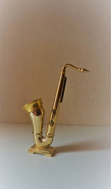Saxofon je vyroben ze zlaté barvy kovu, je lesklý, fotografování se slunečním světlem, aby krásný stín - Fotografie, Obrázek