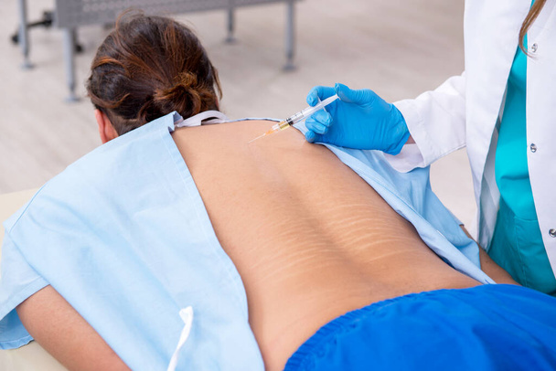 Young back injured man visiting female doctor chiropractor - Foto, Imagem