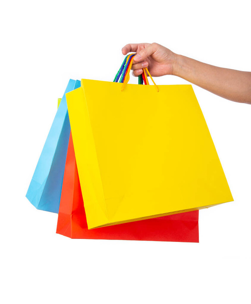 Hand holding multicolored paper bags isolated on white; shopping concept - Photo, Image