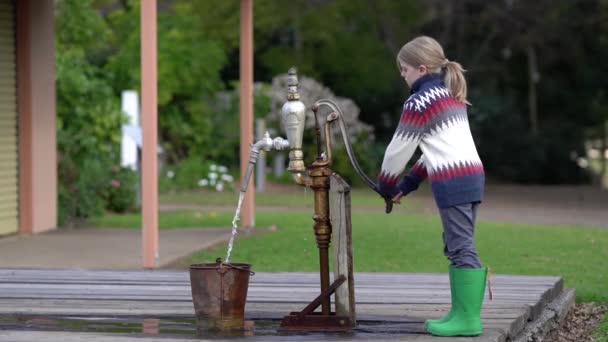 Ein Junge pumpt Wasser in einen alten Eimer. - Filmmaterial, Video