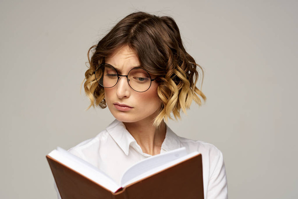 Donna d'affari con blocco note e occhiali su sfondo chiaro acconciatura emozioni di successo - Foto, immagini