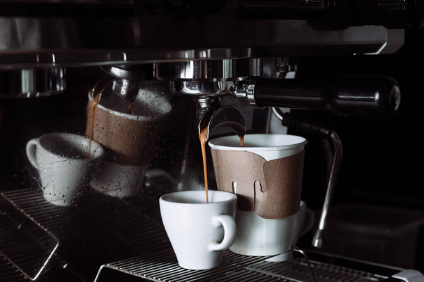 Café recién hecho se vierte de la máquina de café en tazas. Verter, beber. - Foto, Imagen