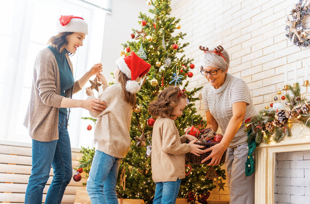 Merry Christmas and Happy Holidays! Granny, mom and daughters near the tree indoors. The morning before Xmas. Portrait of loving family.  - Valokuva, kuva