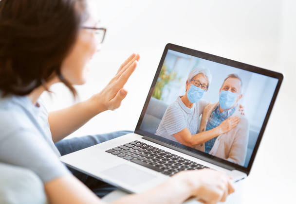 Senior couple wearing face masks and using pc for remote talking during coronavirus and flu outbreak. Virus and illness protection, home quarantine. COVID-2019. - Fotó, kép