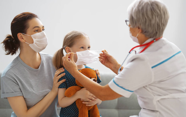Γιατρός, παιδί και μητέρα φορώντας μάσκες προσώπου κατά τη διάρκεια του ιού της στέψης και της γρίπης. Προστασία από ιούς. COVID-2019. Φορώντας μάσκες. - Φωτογραφία, εικόνα