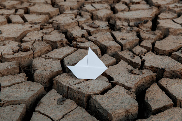 Barco de papel branco em solo seco e seco com rachaduras. Conceito de aquecimento global. - Foto, Imagem