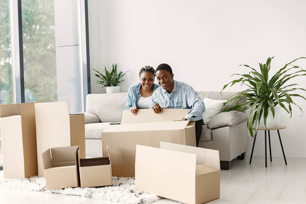 Couple with boxes moving into new home smiling - Foto, Bild