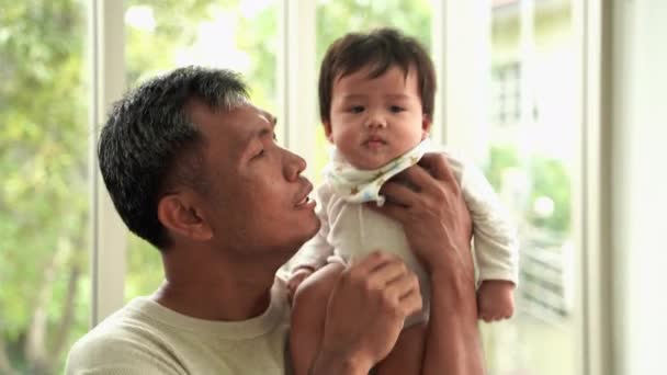 Büyükbaba torunu kucağında ve yanağından öpüyor, Asyalı aile. - Video, Çekim