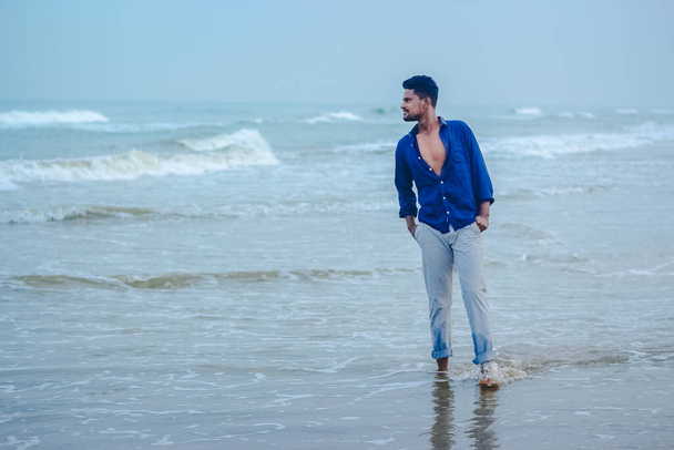 Szexi indiai férfiak modell séta a tengerparton kilátás háttér helyet másolni szöveg. Jóképű és magabiztos férfiak. Szabadtéri portré sétáló fiatal ázsiai indiai férfi a strandon. - Fotó, kép