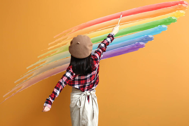 Nettes kleines Mädchen bemalt Regenbogen auf farbigem Hintergrund - Foto, Bild