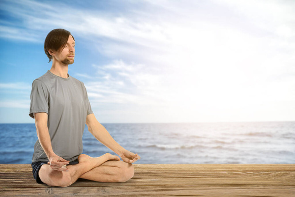 Sportovní muž cvičí jógu u moře - Fotografie, Obrázek