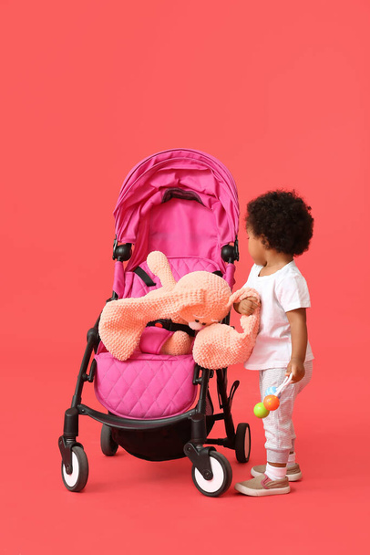 Bébé afro-américain mignon avec poussette sur fond de couleur - Photo, image