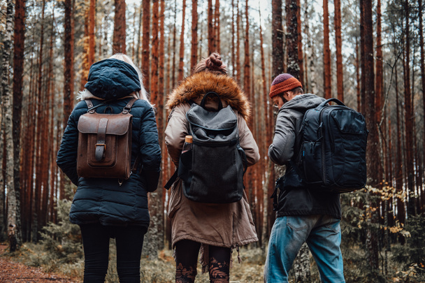 Хлопець і дві дівчини з рюкзаками в осінньому лісі
 - Фото, зображення