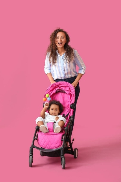 African-American woman and her cute baby in stroller on color background - Photo, Image