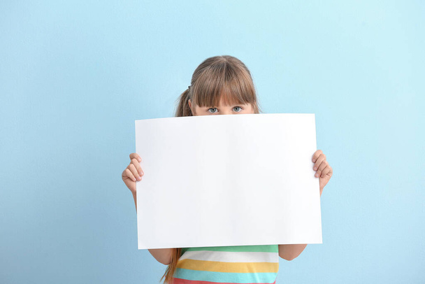 Little girl with blank paper sheet on color background - Photo, Image