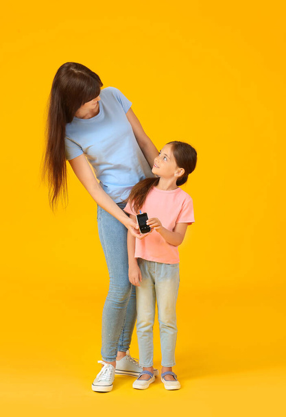 Moeder en haar diabetische dochter met glucometer op kleur achtergrond - Foto, afbeelding
