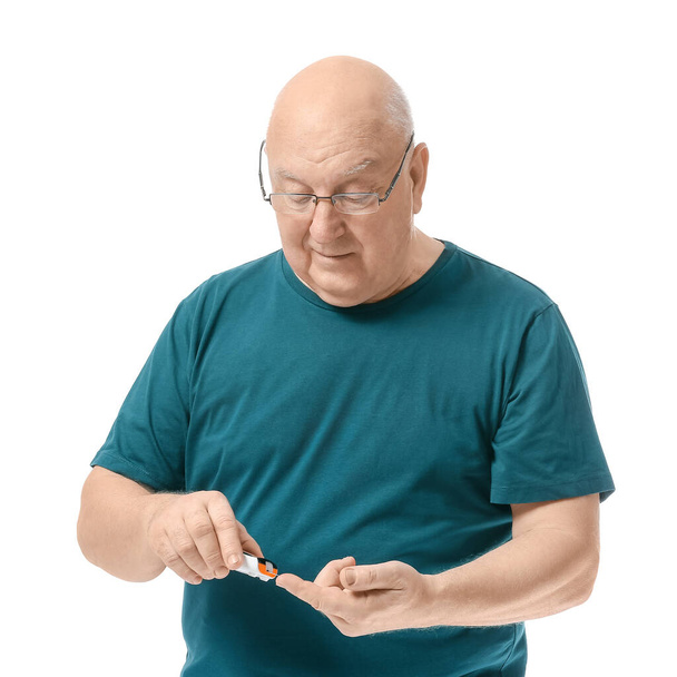 Uomo diabetico anziano che controlla il livello di zucchero nel sangue su sfondo bianco - Foto, immagini