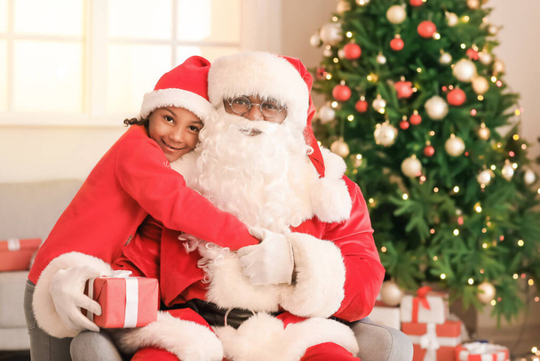 Αφρο-Αμερικανός Άγιος Βασίλης με χαριτωμένο κορίτσι στο σπίτι την παραμονή των Χριστουγέννων - Φωτογραφία, εικόνα