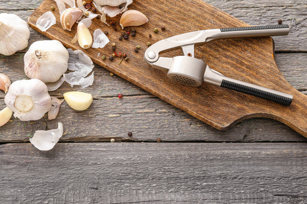 Garlic press with cloves and spices on table - Zdjęcie, obraz