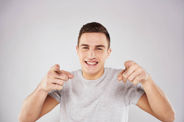 Man in een wit t-shirt emoties gebaren met handen close-up bijgesneden uitzicht licht achtergrond - Foto, afbeelding