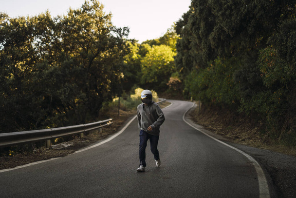 A closeup shot of a young man running in the middle of a street wearing a helmet - Photo, Image