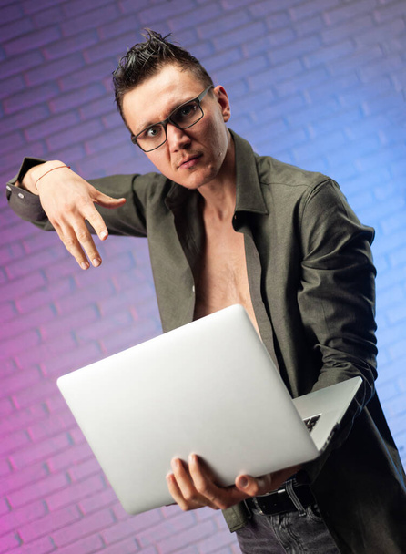 crazy man with glasses and laptop on a bright neon background - Photo, image