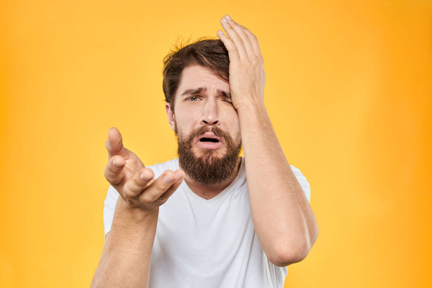 A man in a white t-shirt gestures with his hands studio lifestyle yellow background emotions - Foto, Bild