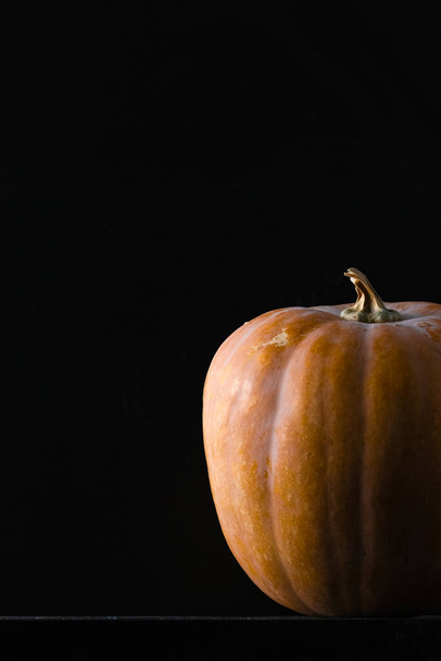 A vertical shot of a pumpkin on a black background - Photo, Image