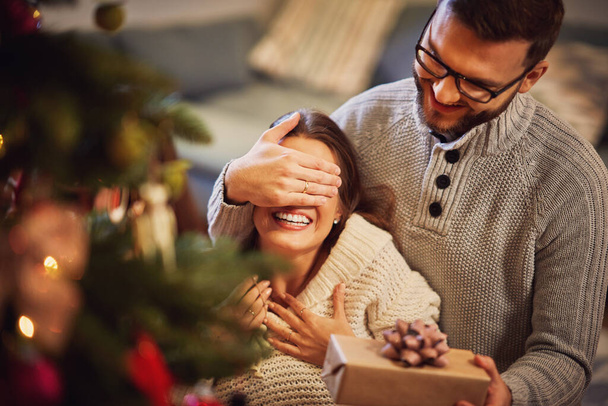 Pareja adulta con regalo sobre árbol de Navidad - Foto, Imagen