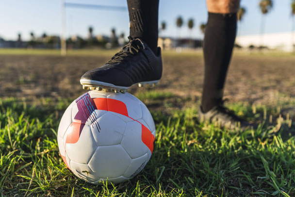 A footballer's foot on the ball on the lawn, the concept of a healthy sporty lifestyle - Фото, изображение